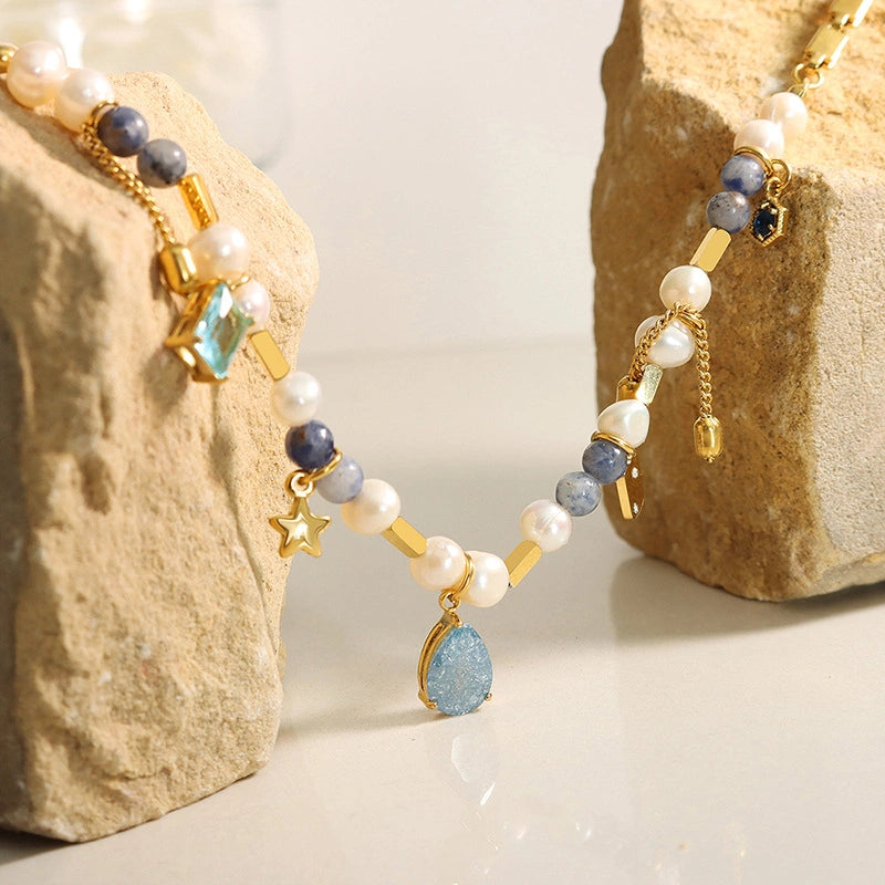 Flat lay of asymmetric freshwater pearl necklace with natural stones and vintage geometric links