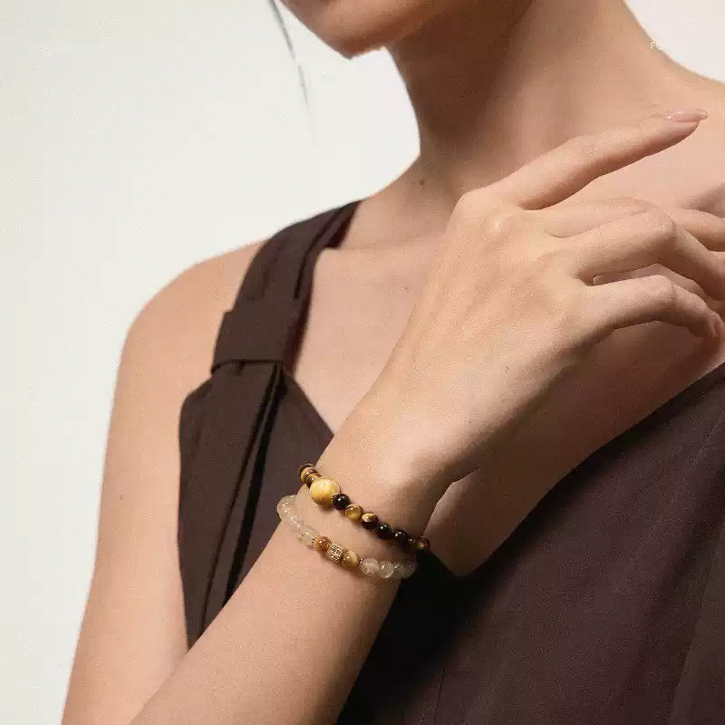 Close-up of natural crystal beaded bracelets featuring gold spacer beads and polished tiger eye stones