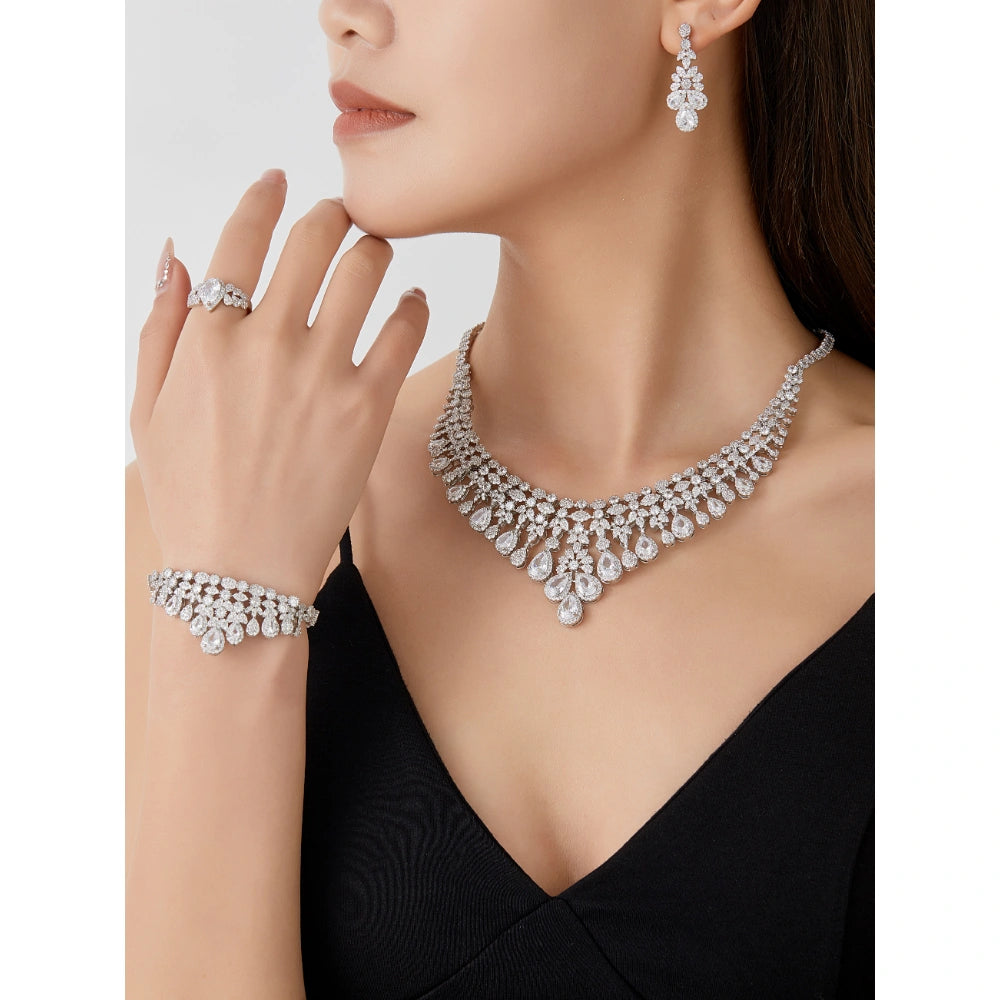 Crystal clear cubic zirconia bridal jewelry set with silver-tone finish. Includes necklace, ring, earrings, and bracelet for weddings and formal wear