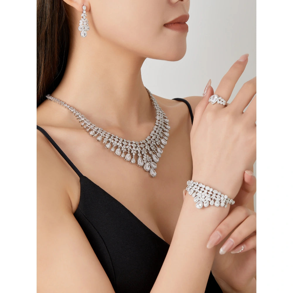 Crystal clear cubic zirconia bridal jewelry set with silver-tone finish. Includes necklace, ring, earrings, and bracelet for weddings and formal wear