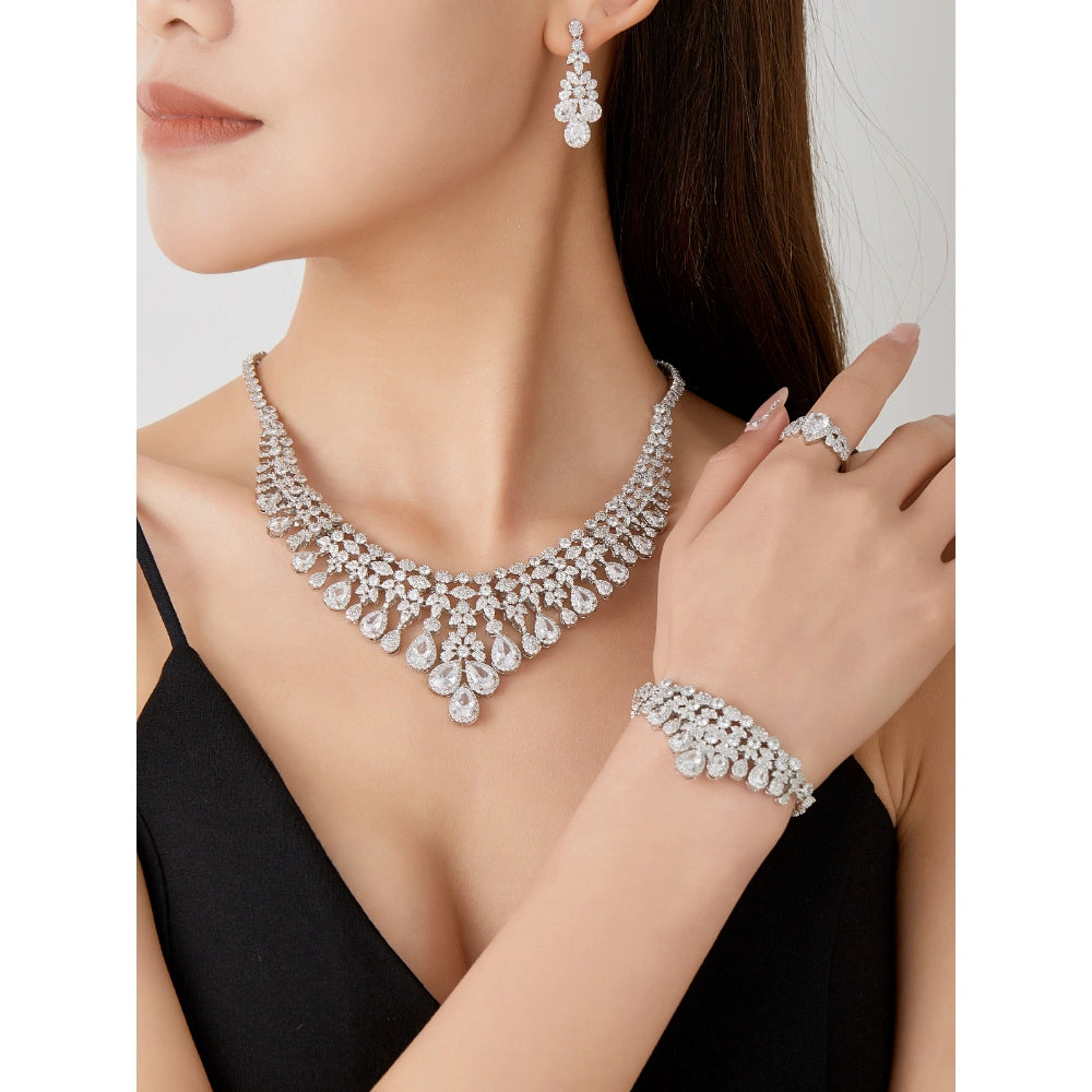 Crystal clear cubic zirconia bridal jewelry set with silver-tone finish. Includes necklace, ring, earrings, and bracelet for weddings and formal wear