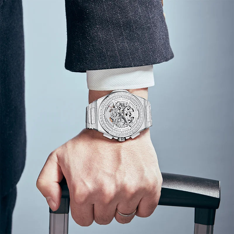 Mens Frost Wings mechanical watch worn on wrist holding a luggage handle