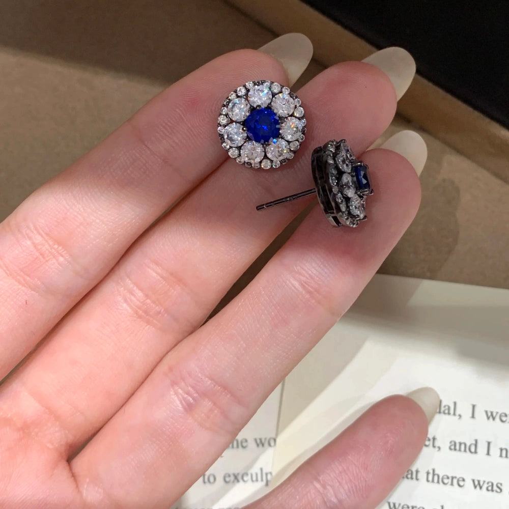 Pair of lab-grown blue diamond halo stud earrings in a flat lay, showing the royal blue cluster vintage design