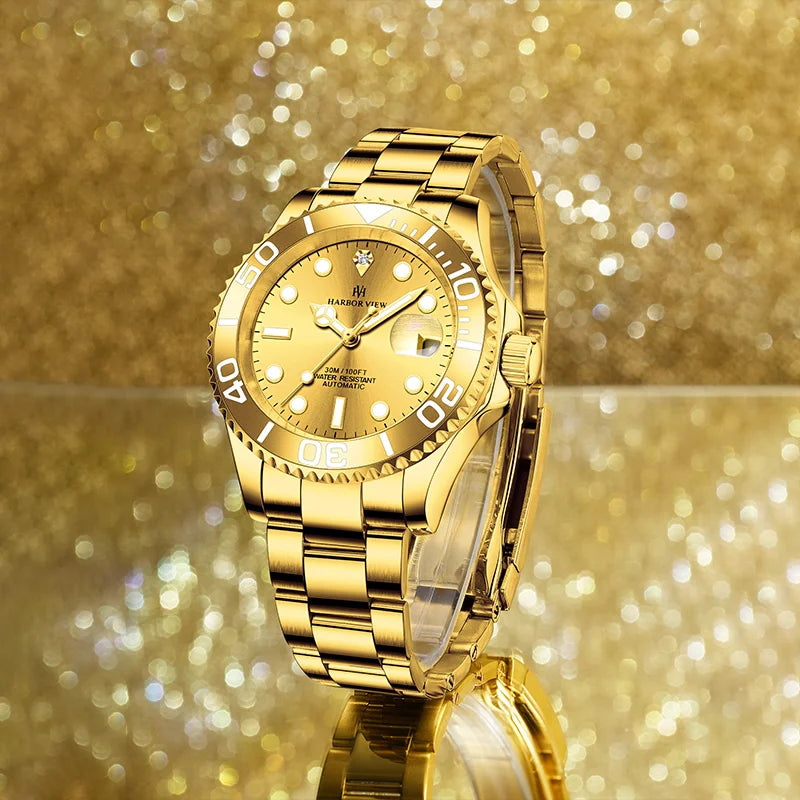 Front angled display of a luxury gold automatic mechanical watch against a sparkling golden background