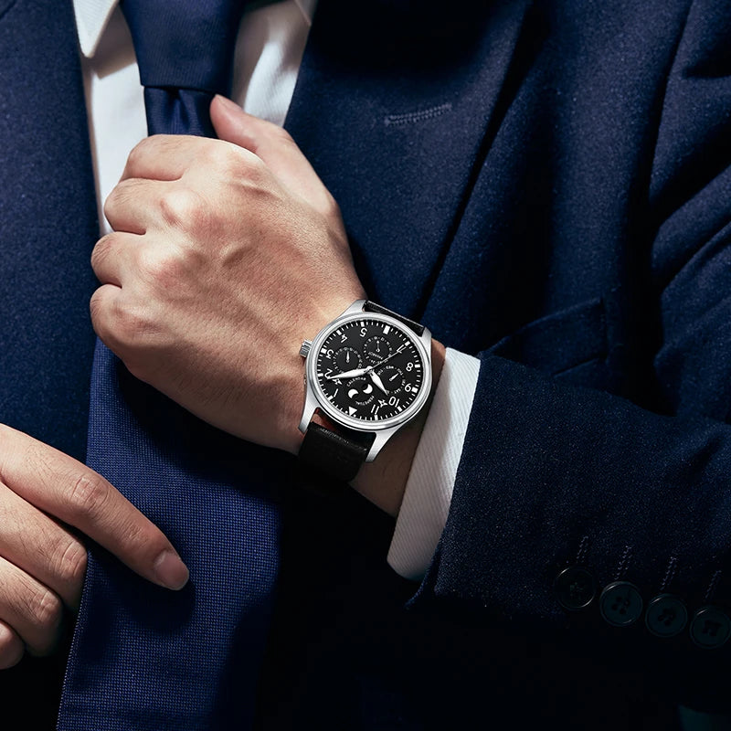 Close-up wrist shot of man wearing black dial aviator watch with navy blue business suit