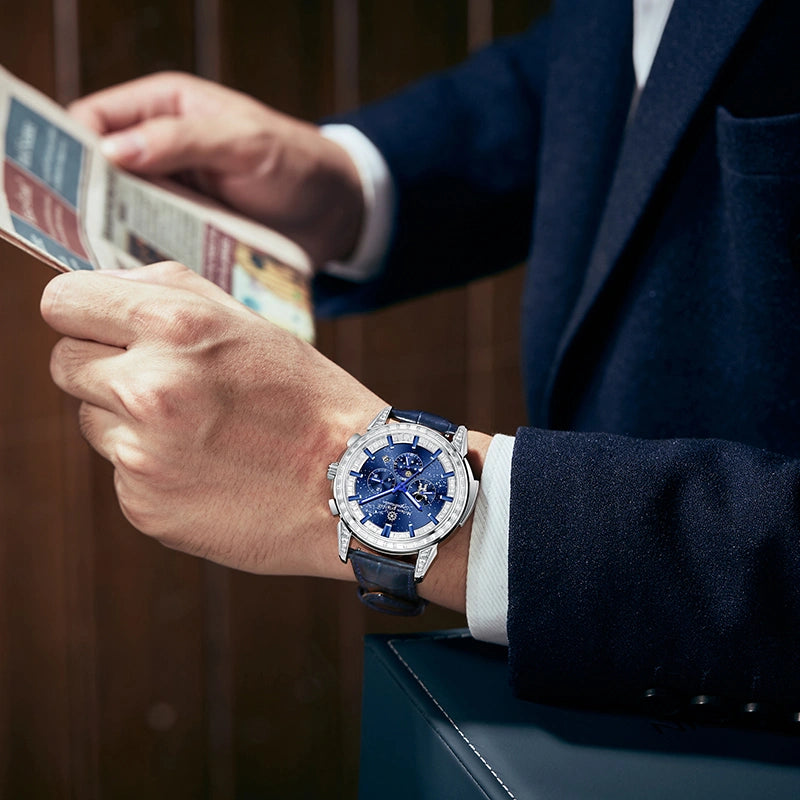 Man wearing blue dial celestial watch with a navy suit reading newspaper