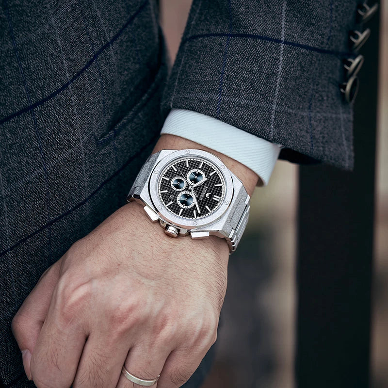 Wrist shot of gentleman wearing frosted octagonal steel watch with pinstripe suit jacket