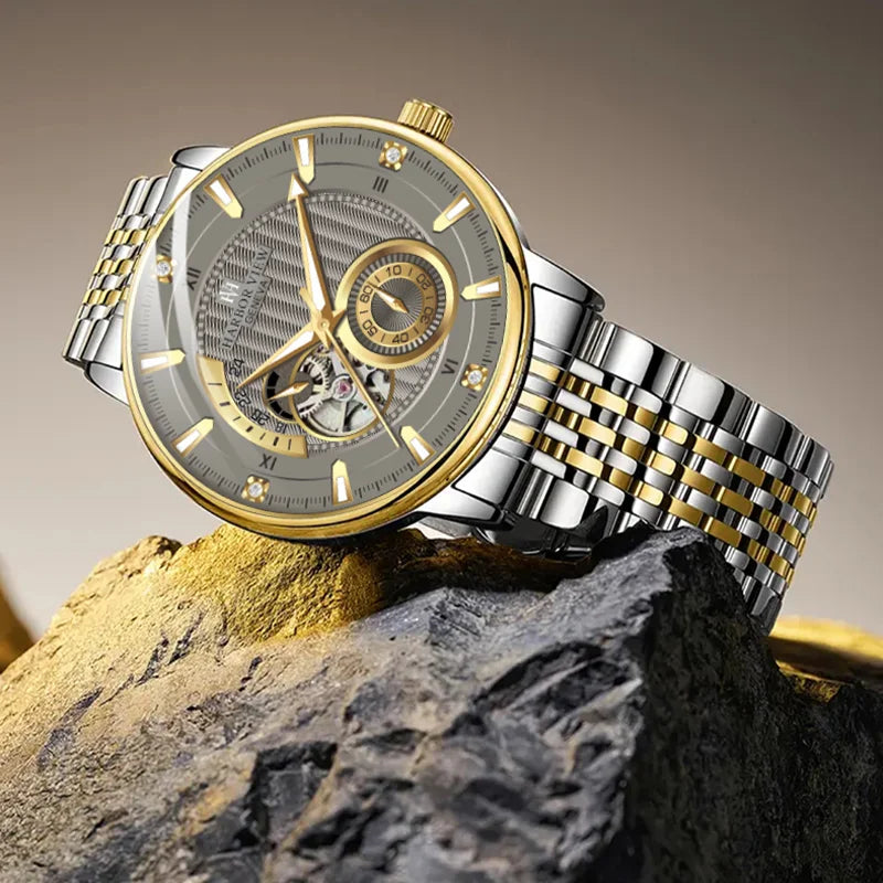 Two-tone skeleton mechanical watch displayed on a rough mineral rock surface
