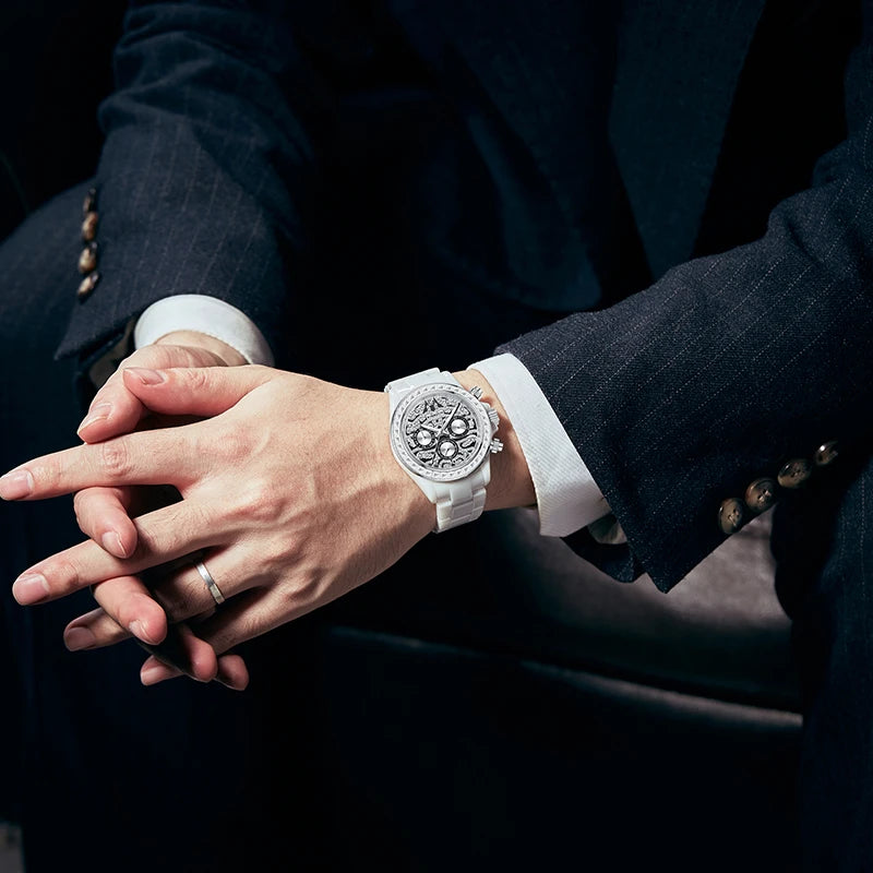 Close-up of man wearing white ceramic watch with dark suit and interlocked hands