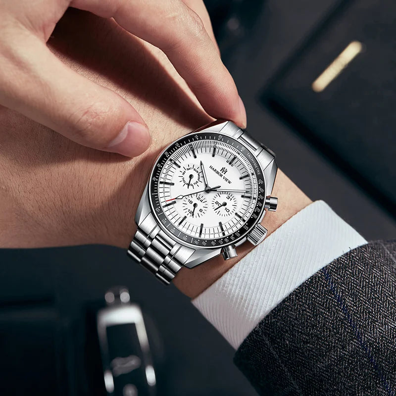 Wrist shot of a man wearing a white panda dial mechanical watch with a suit cuff