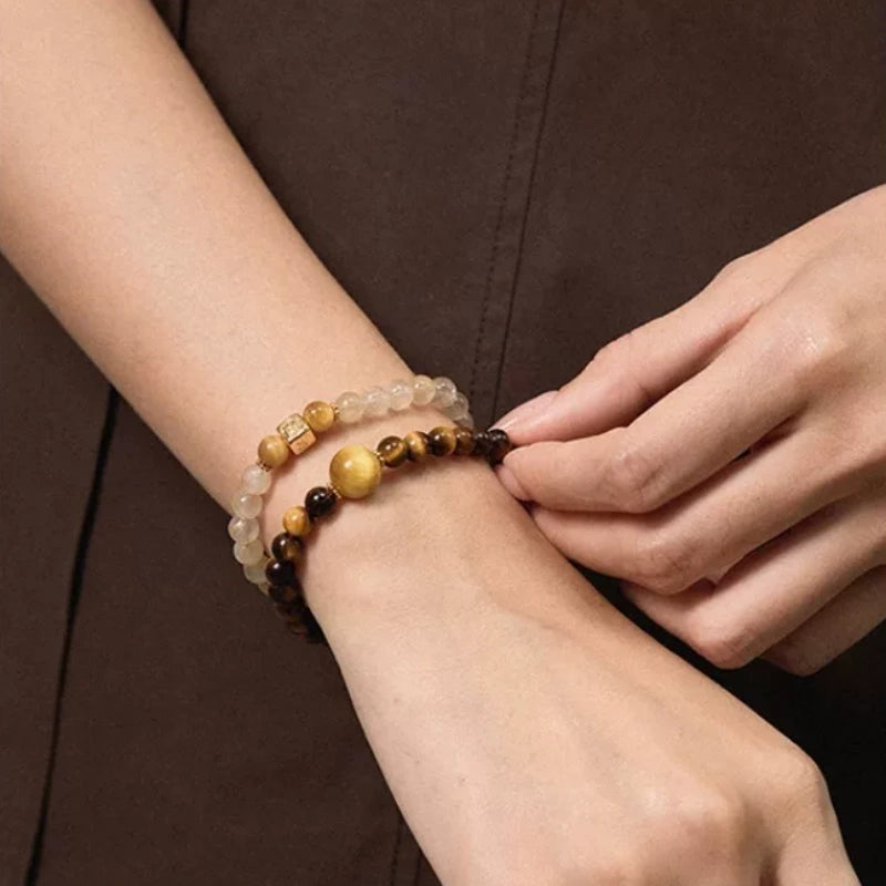 Woman wearing a stack of natural stone beaded bracelets with tiger eye and crystal beads on her wrist