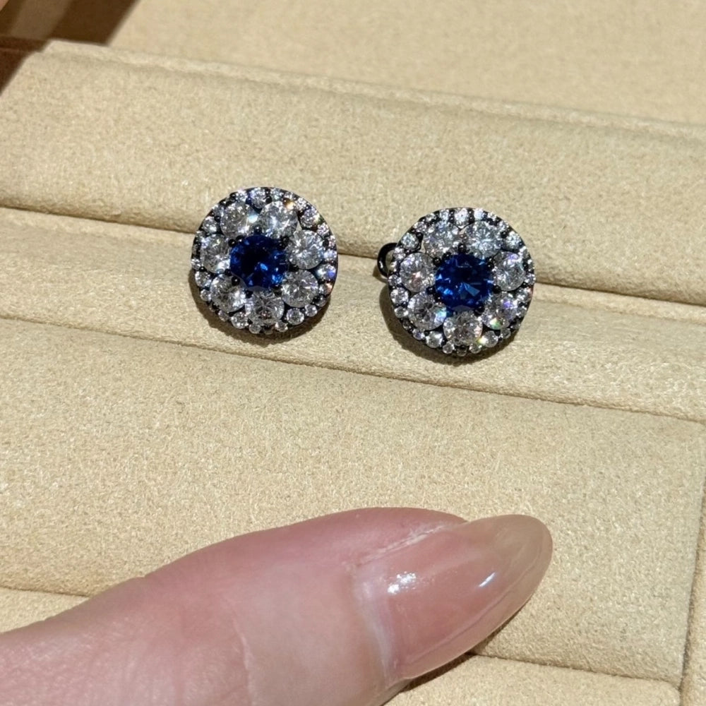 Close-up of vintage light luxury blue diamond cluster stud earrings showing concentric white stone halos