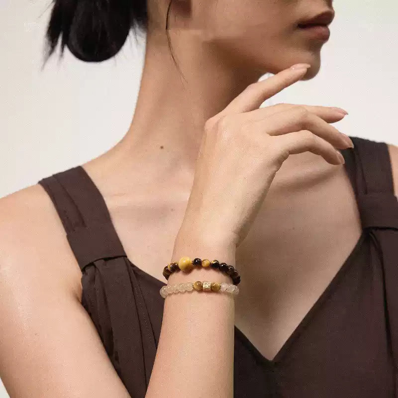 Model wearing layered tiger eye and crystal beaded bracelets, styled with a brown dress for a natural look